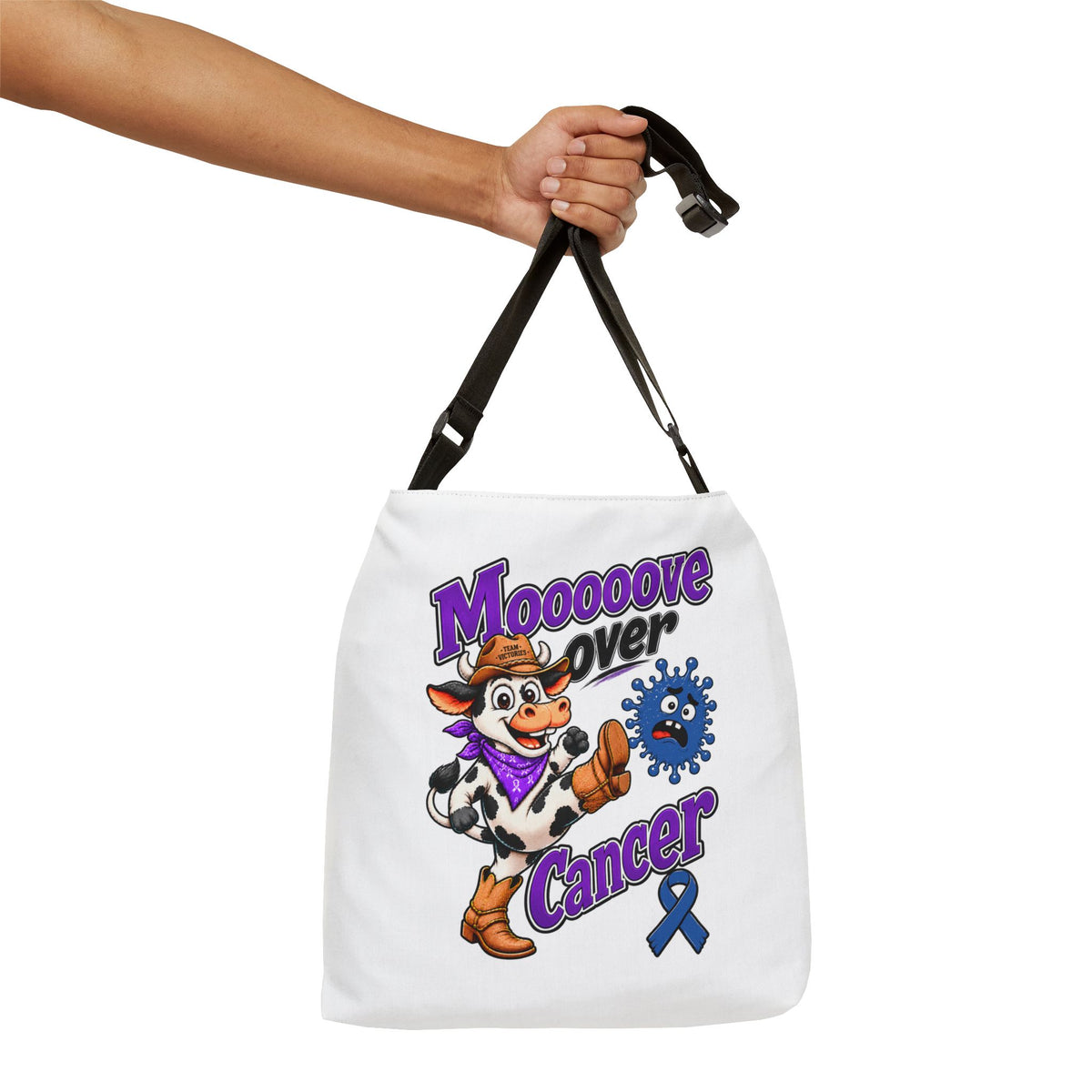 Hand holding the Moooove Over Cancer shoulder tote by its adjustable strap