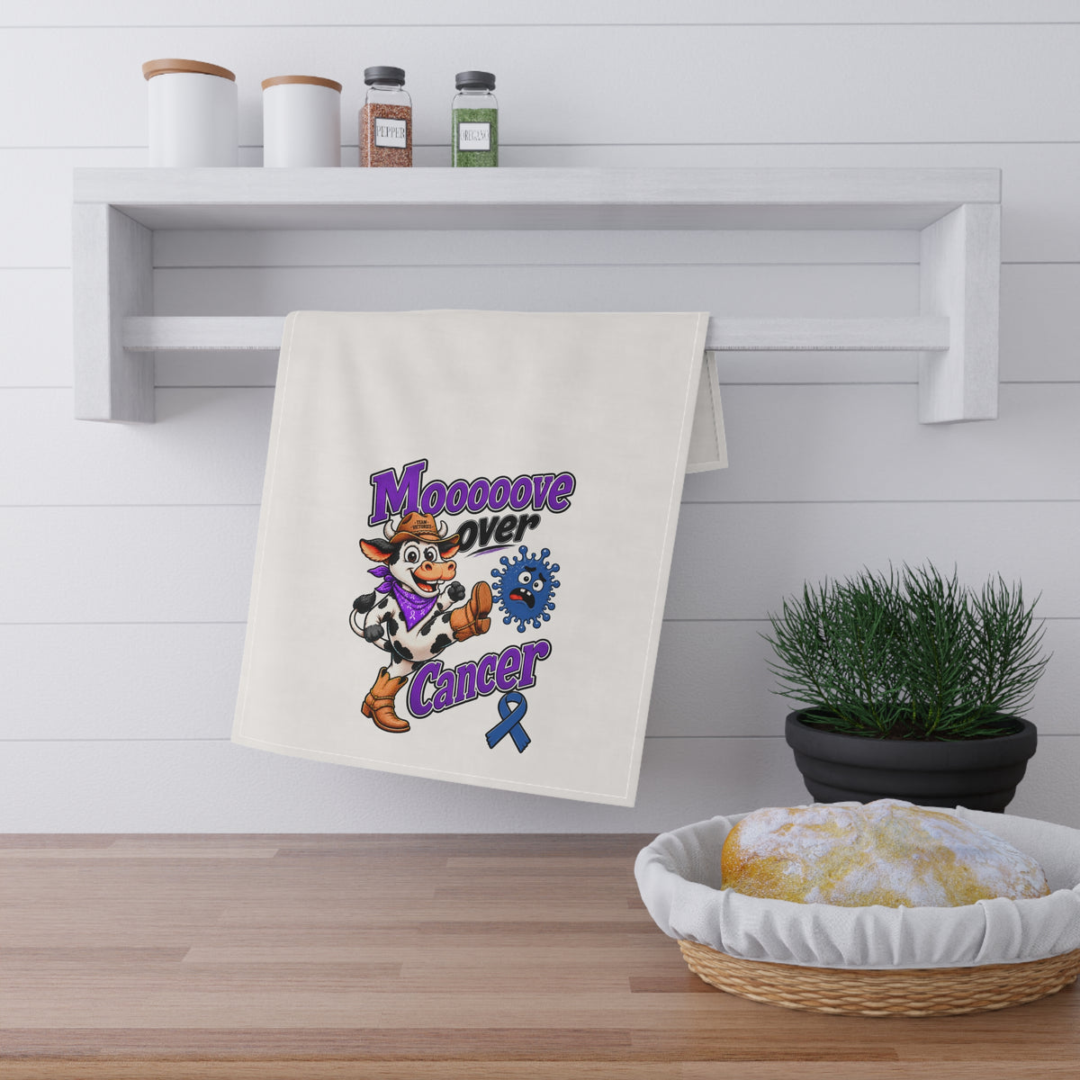 Moooove Over Cancer tea towel displayed in a kitchen with purple cancer awareness design
