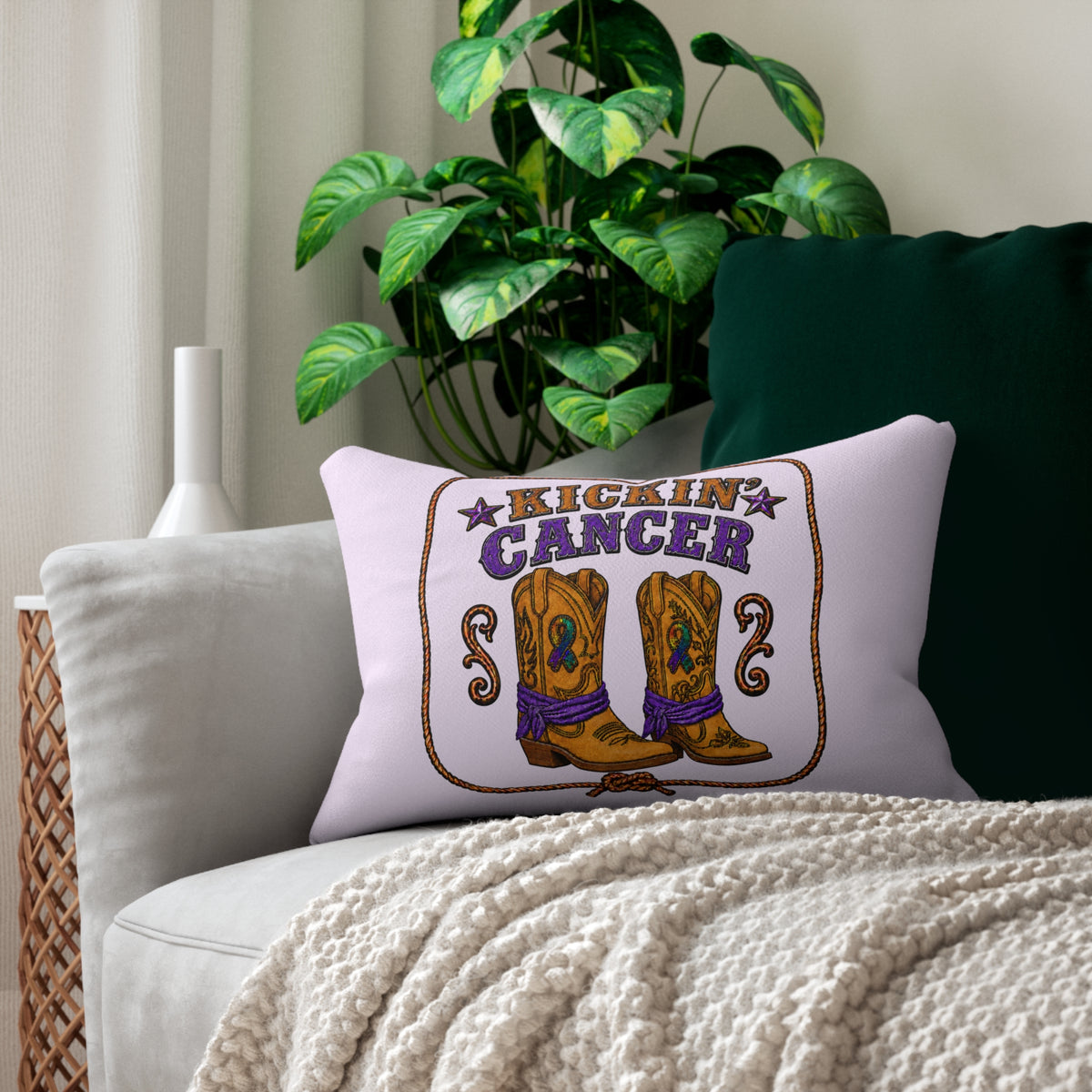 Kickin' Cancer lumbar pillow with western boot artwork arranged on a chair beside a houseplant