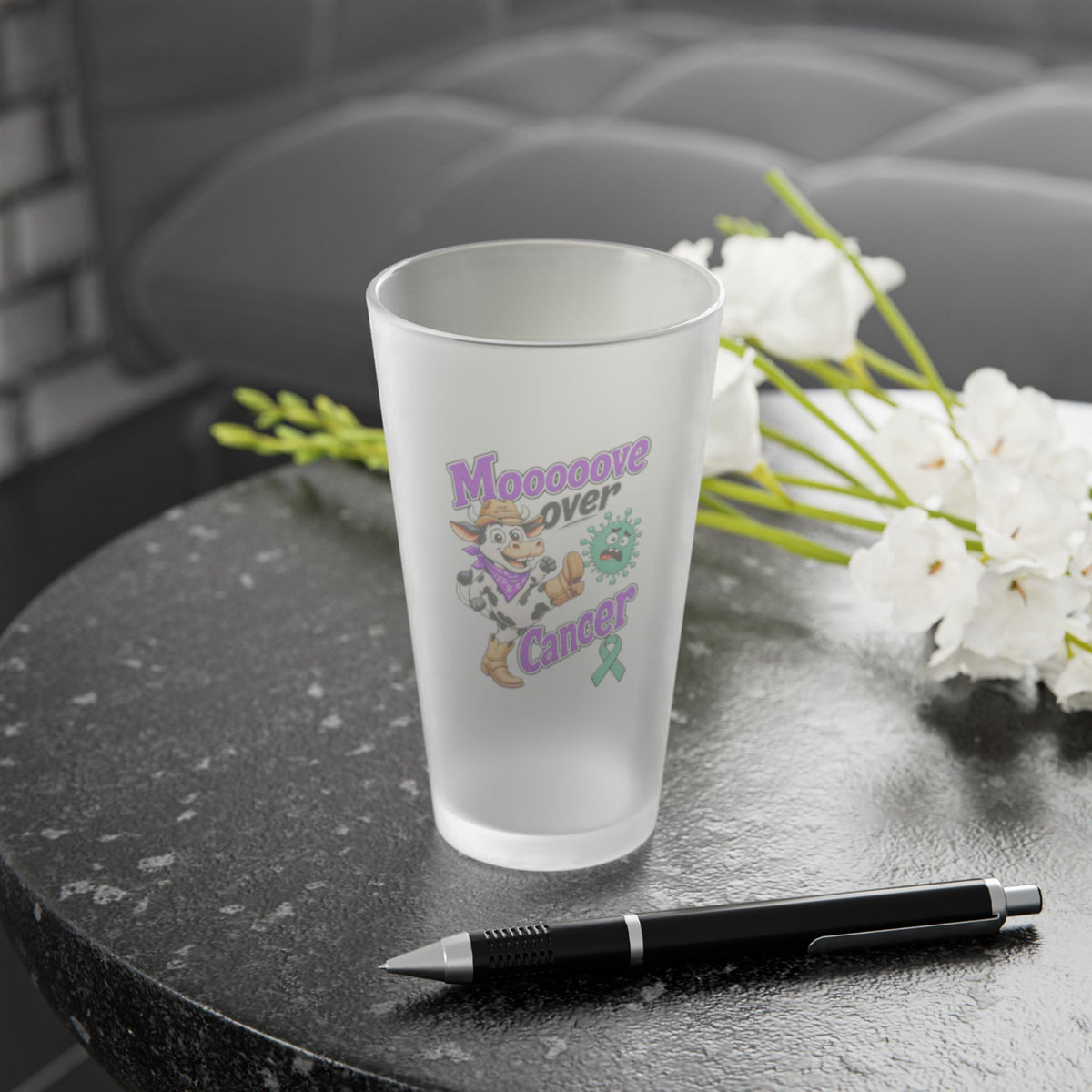Moooove Over Cancer frosted pint glass displayed beside flowers and a pen