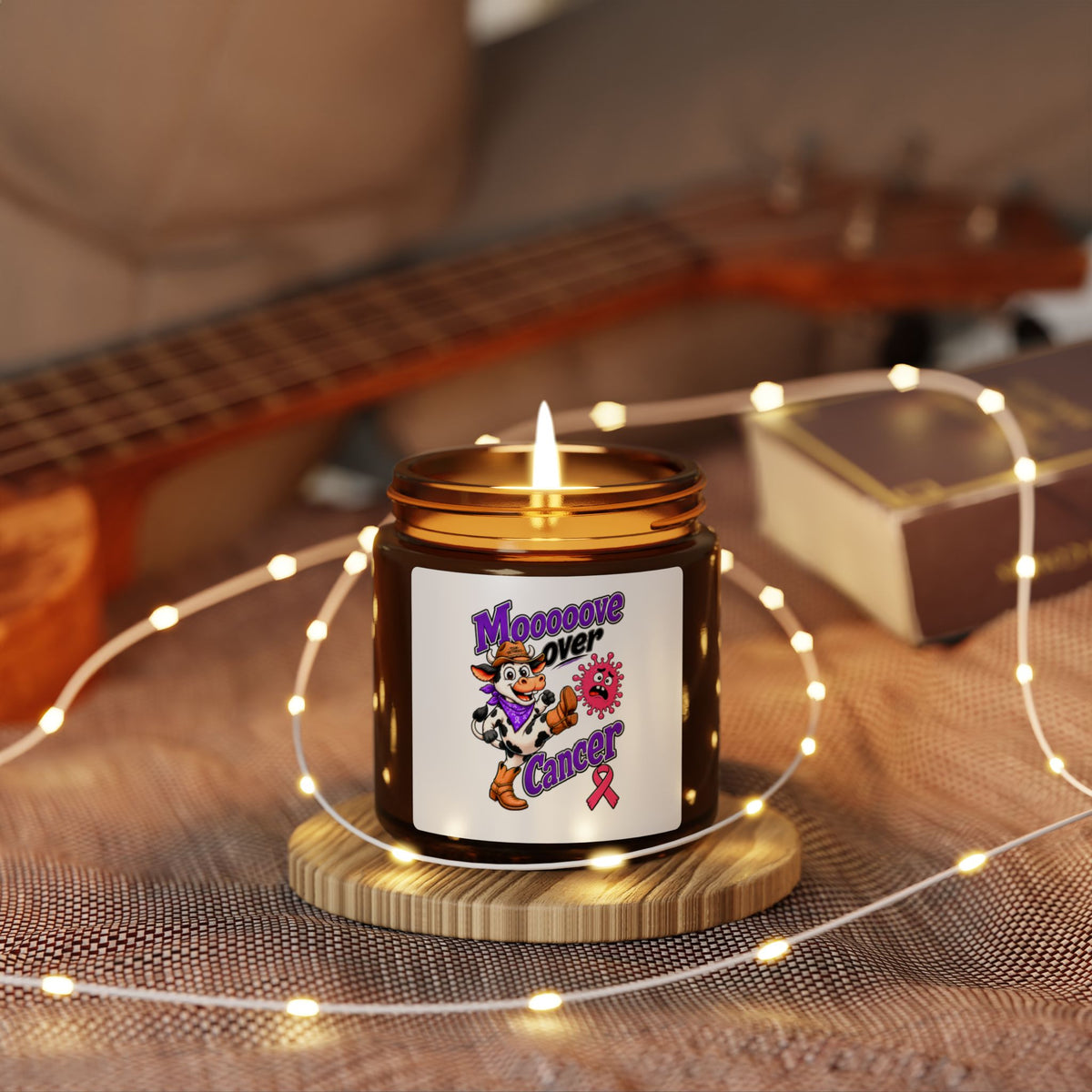 Moooove Over Cancer candle glowing in a cozy setting with a Breast Cancer awareness ribbon label