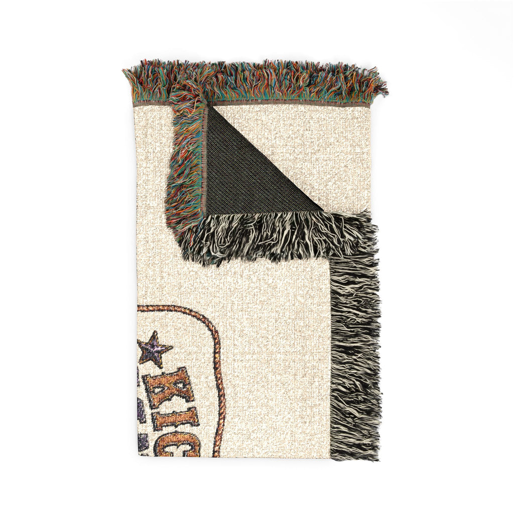 Close-up of the blanket corner with woven texture, multicolor fringe, and partial Kickin' Cancer artwork
