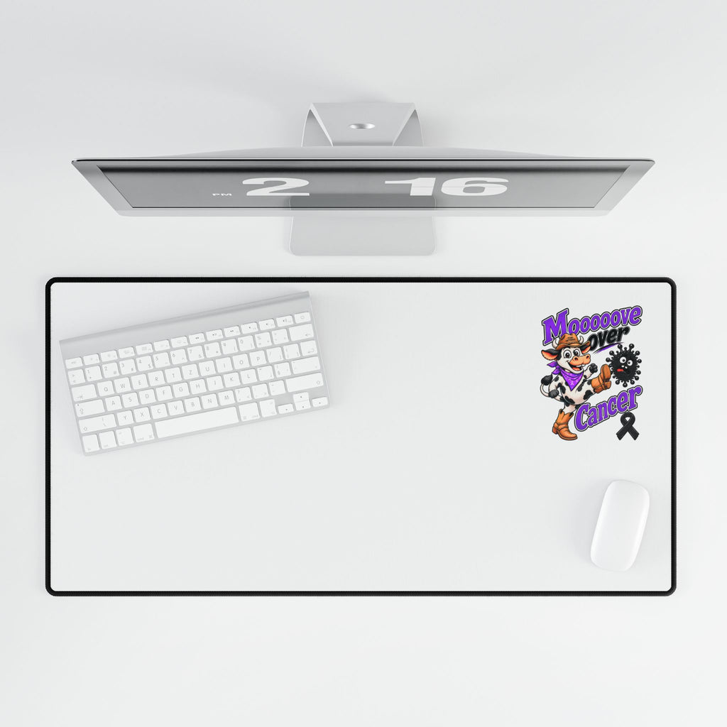 Moooove Over Cancer desk mat shown beneath a monitor with keyboard and mouse