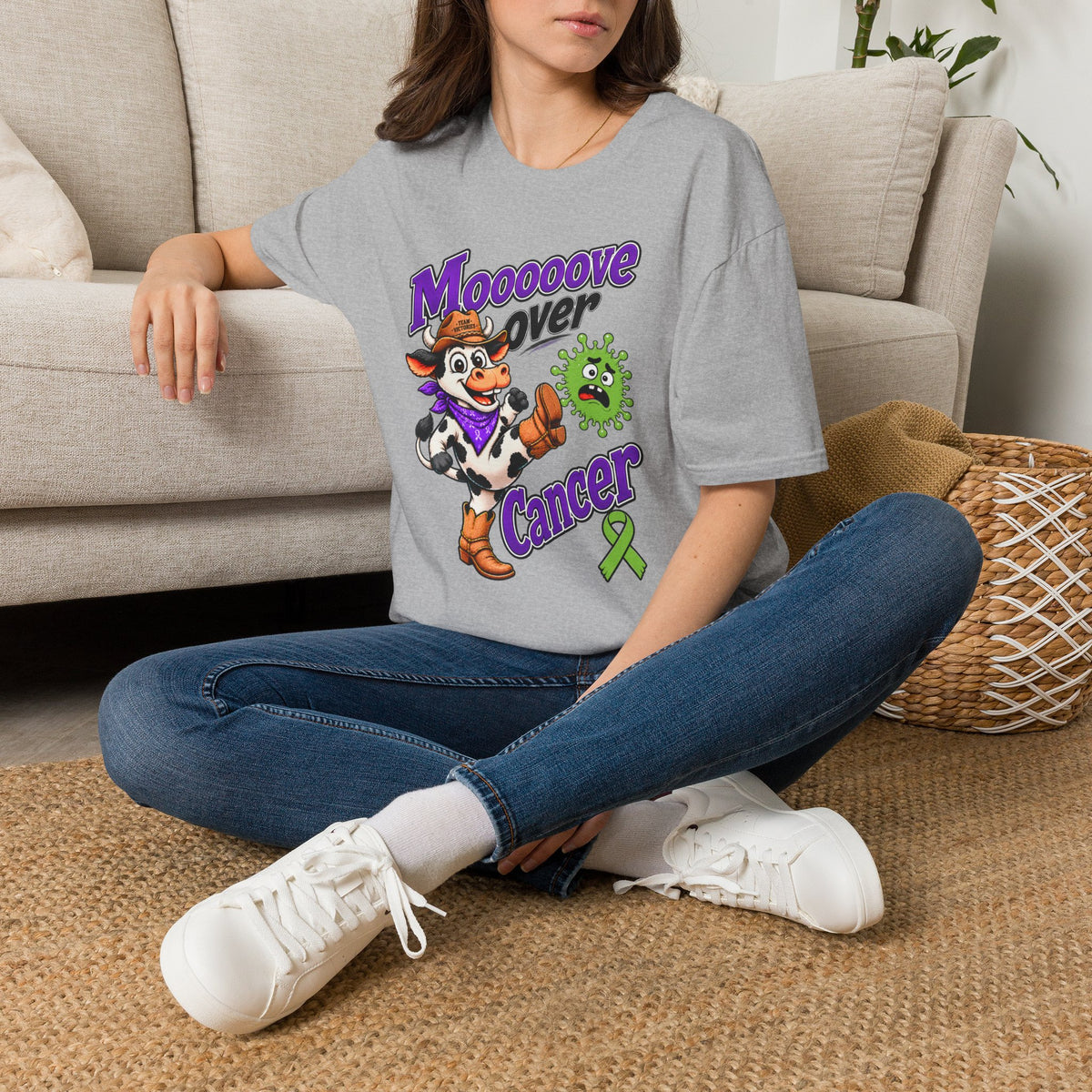 Woman seated wearing gray Moooove Over Cancer T-shirt