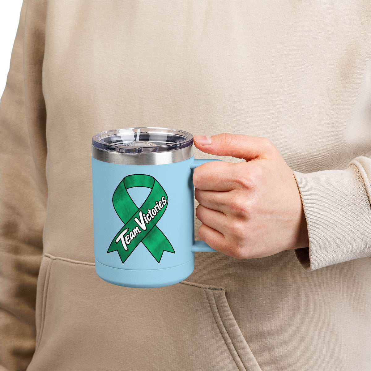 Person holding blue Team Victories mug with green Liver Cancer awareness ribbon