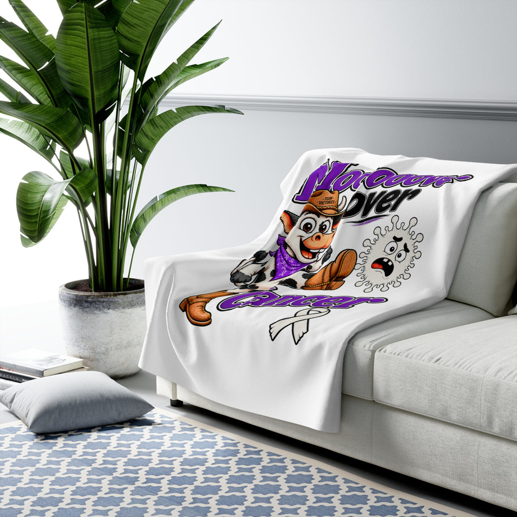 Moooove Over Cancer blanket draped over a sofa with Lung Cancer awareness ribbon artwork