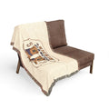 Kickin' Cancer woven cotton blanket draped over a brown chair with cowboy boot artwork and colorful fringe