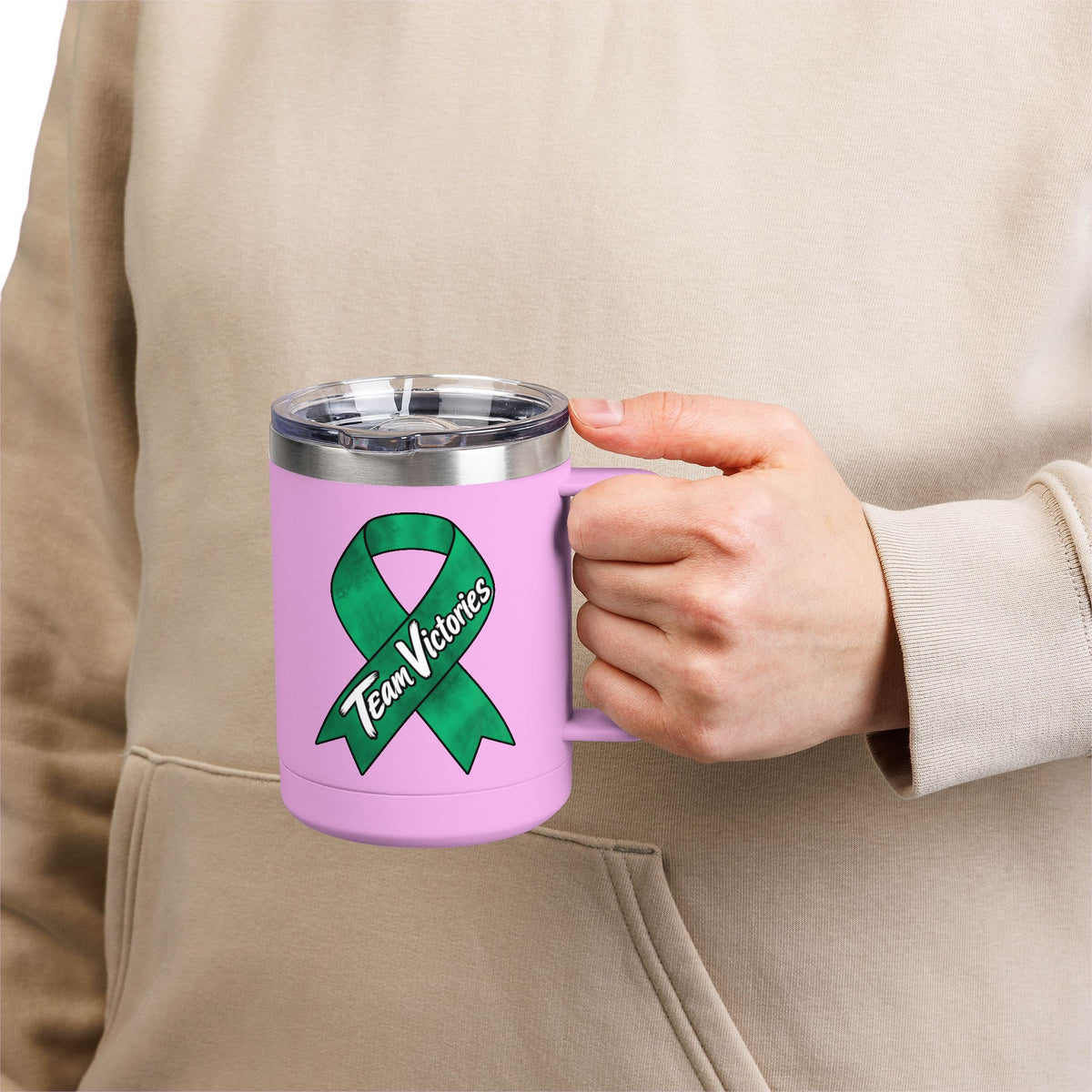 Person holding pink Team Victories mug with green Liver Cancer awareness ribbon
