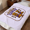 Lavender Kickin' Cancer plush blanket spread across a bed with cowboy boot and awareness artwork