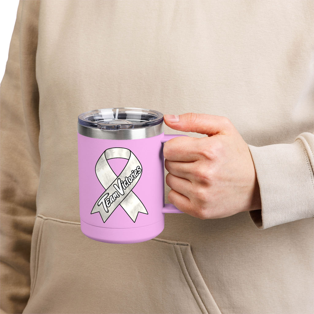 Person holding a pink Team Victories mug with a Lung Cancer awareness ribbon