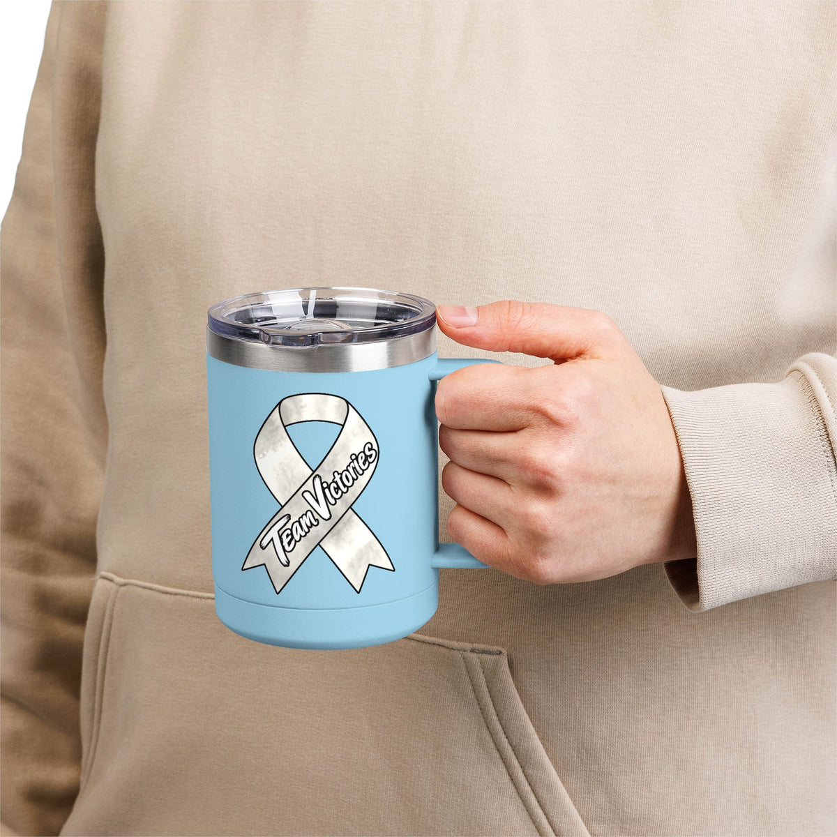 Person holding a blue Team Victories mug with a Lung Cancer awareness ribbon