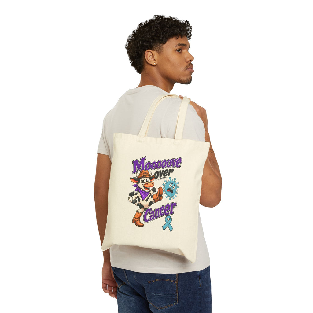 Moooove Over Cancer canvas tote bag worn over the shoulder, showing the front cow graphic