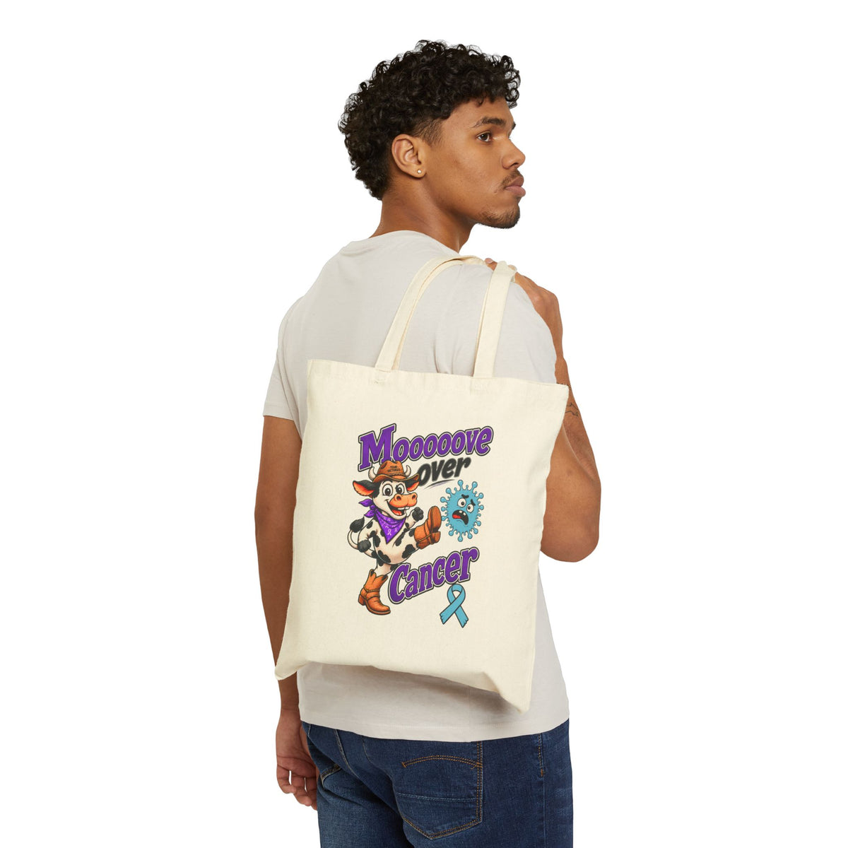 Moooove Over Cancer canvas tote bag worn over the shoulder, showing the front cow graphic