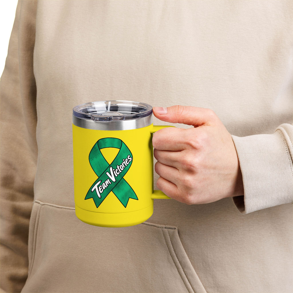 Person holding yellow Team Victories mug with green Liver Cancer awareness ribbon