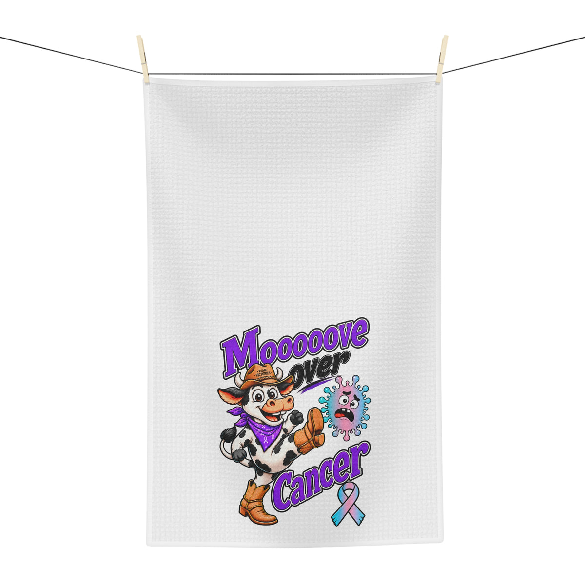 Moooove Over Cancer tea towel hanging outdoors with cow character and colorful ribbon design