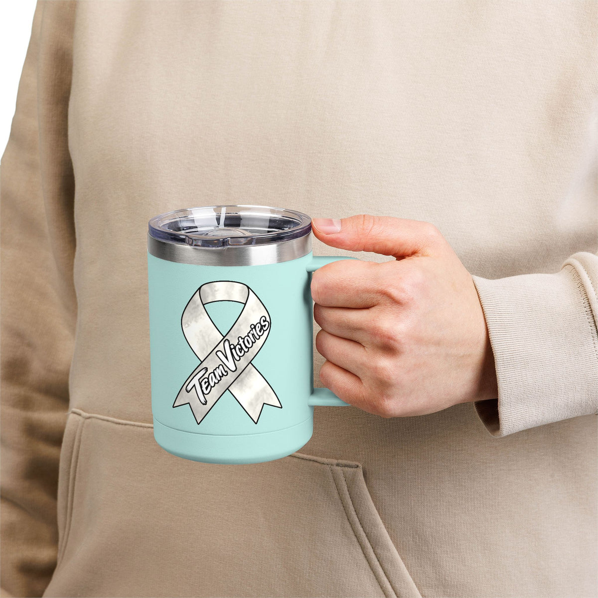 Person holding a light blue Team Victories mug with a Lung Cancer awareness ribbon