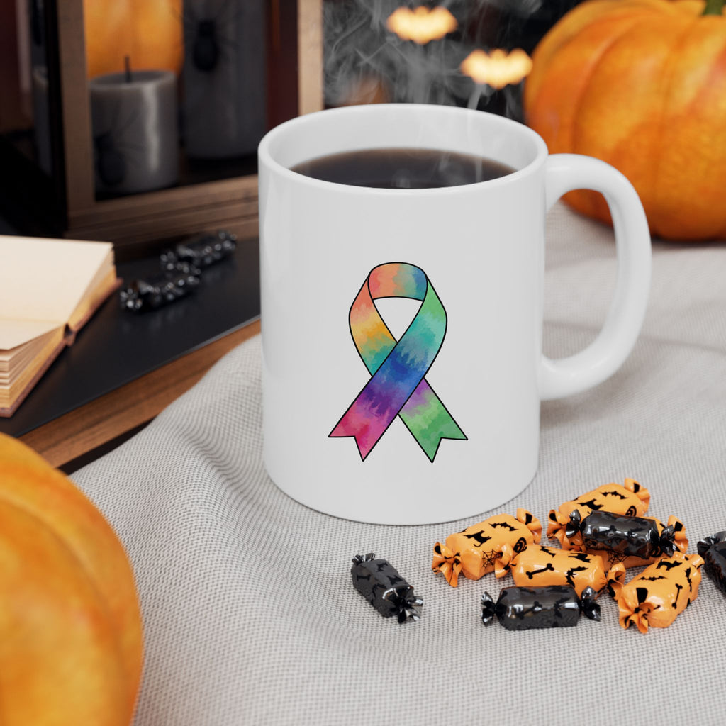 White mug with colorful awareness ribbon beside a cup of coffee