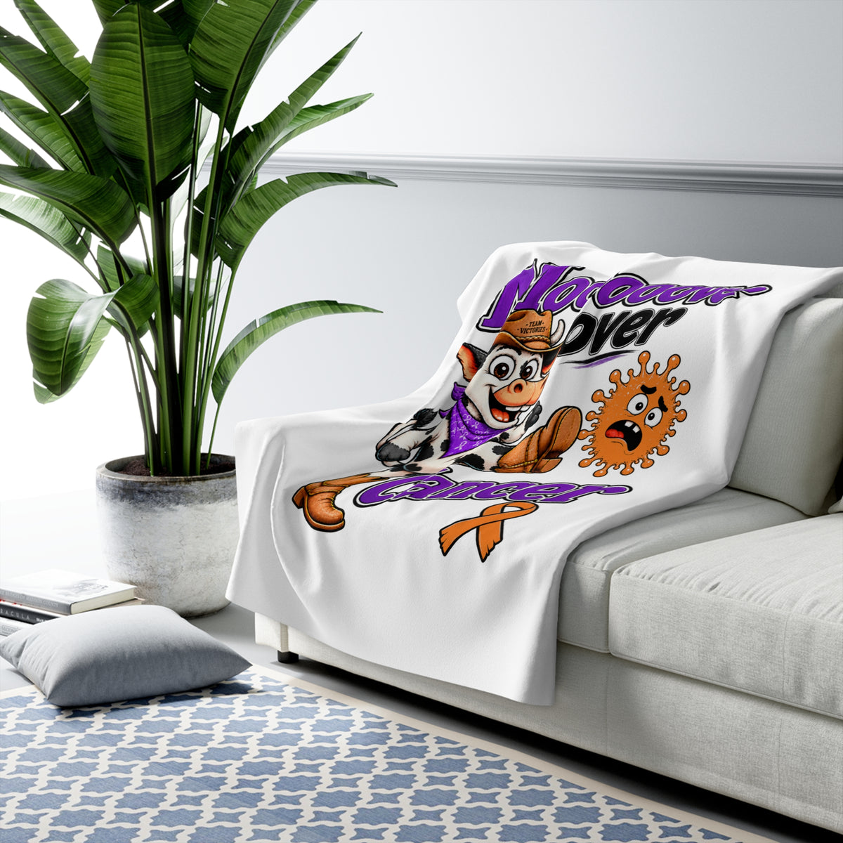 Moooove Over Cancer sherpa blanket draped over a sofa with cow artwork