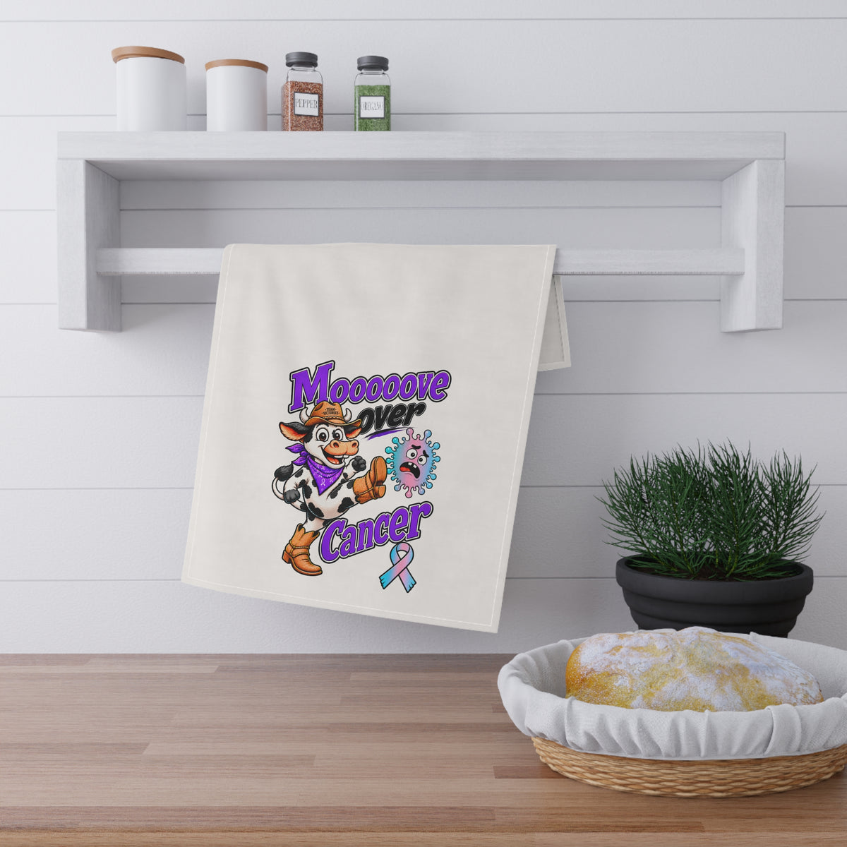 Moooove Over Cancer tea towel displayed in a kitchen beside baked goods