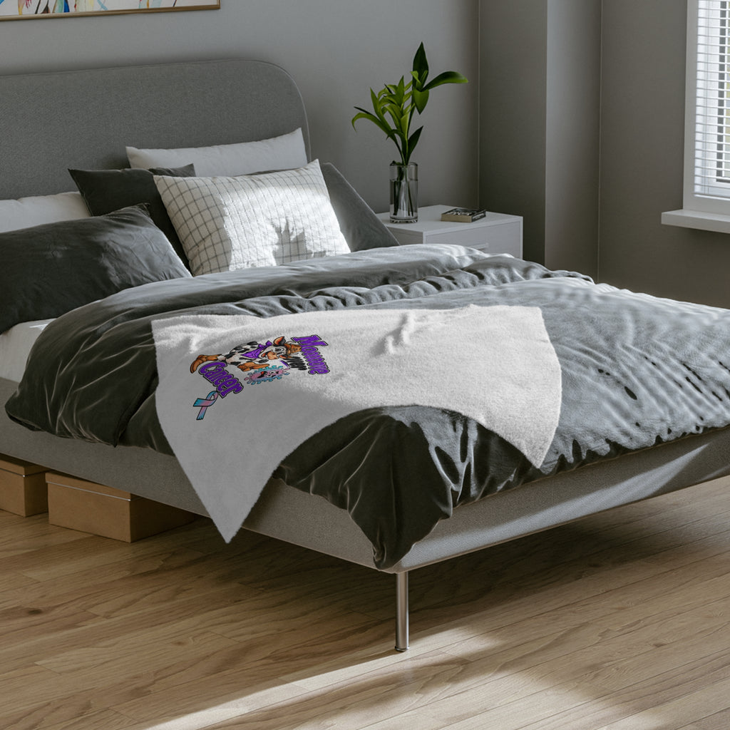 Moooove Over Cancer blanket displayed across a bed with artwork visible