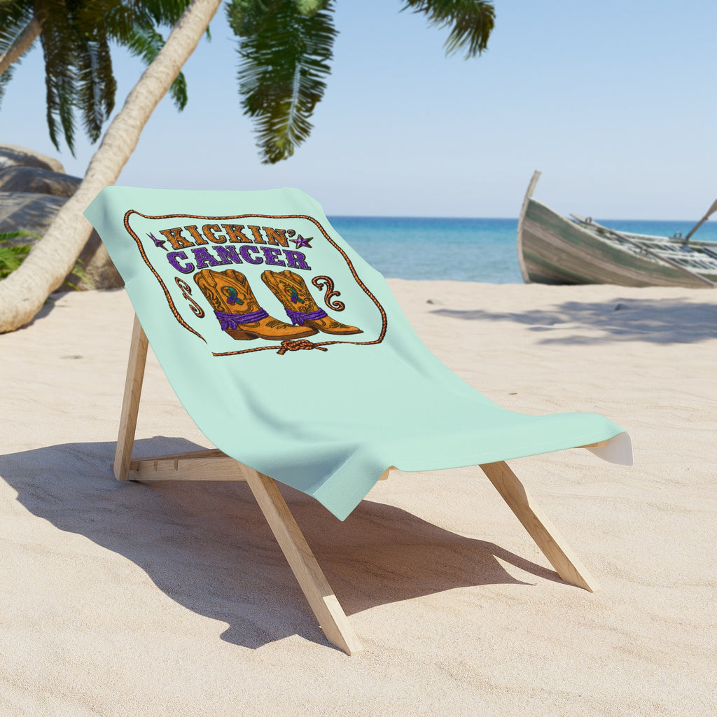 Mint Kickin' Cancer towel draped on a beach chair beside the ocean
