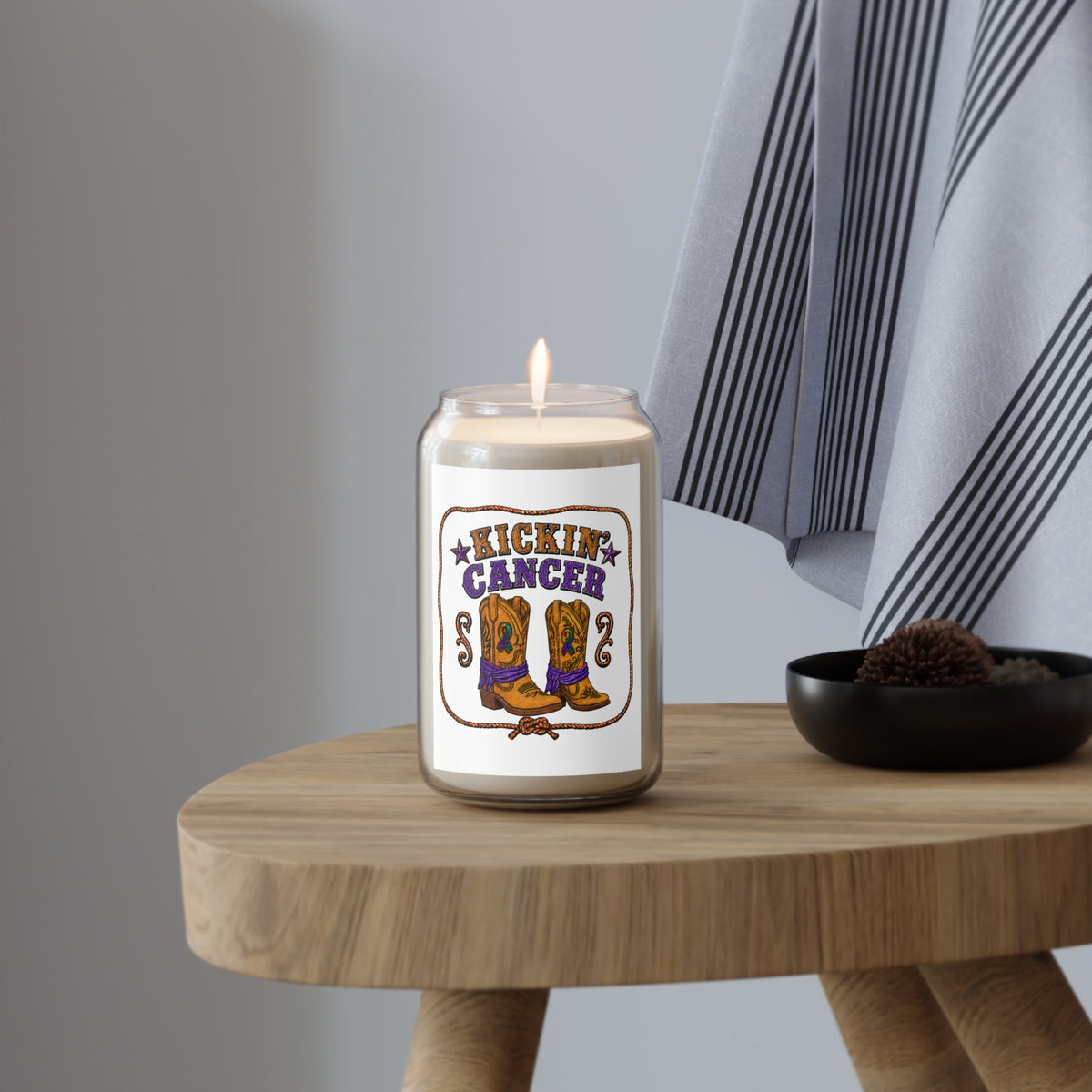 Kickin' Cancer soy candle with western boot artwork displayed on a round wood table