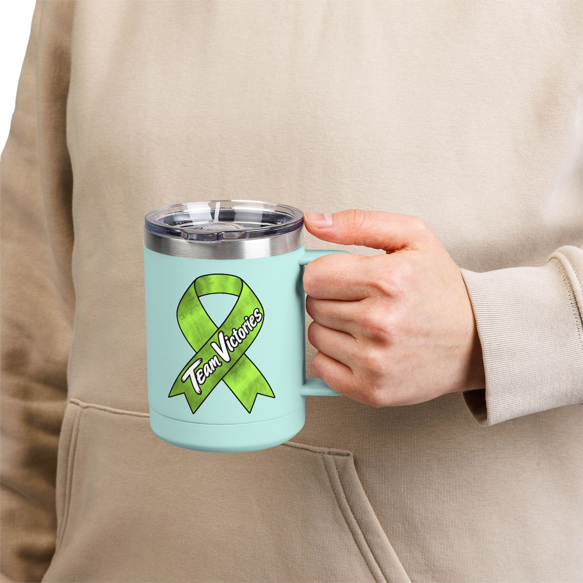 Person holding aqua Team Victories mug with Non-Hodgkin/Lymphoma Cancer awareness ribbon