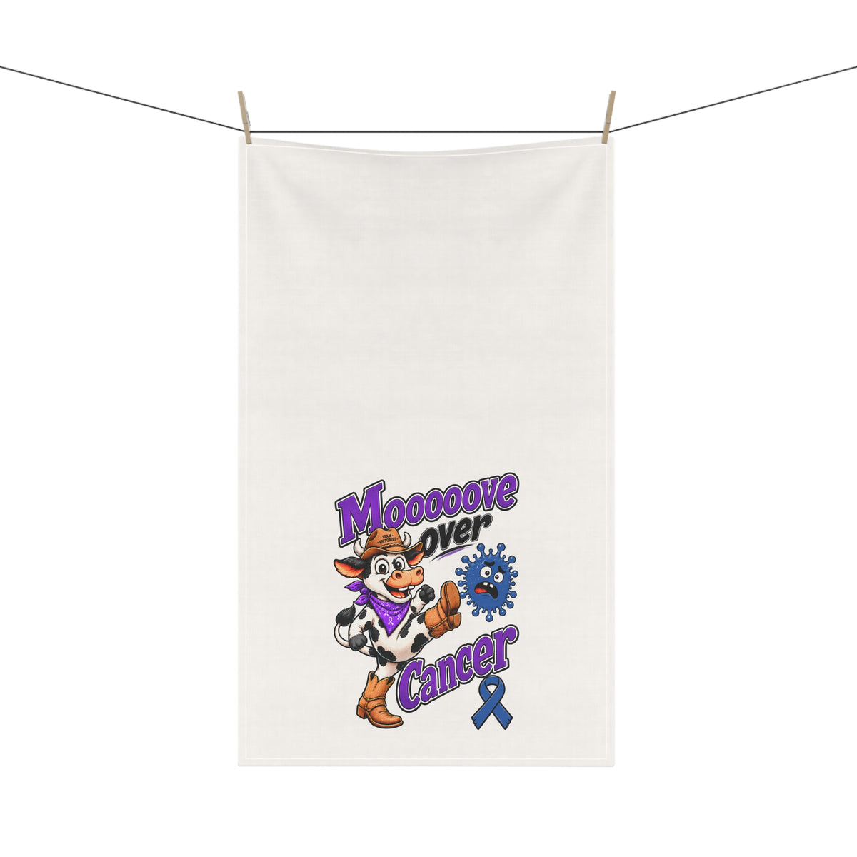 Moooove Over Cancer tea towel hanging on a clothesline with cow design visible