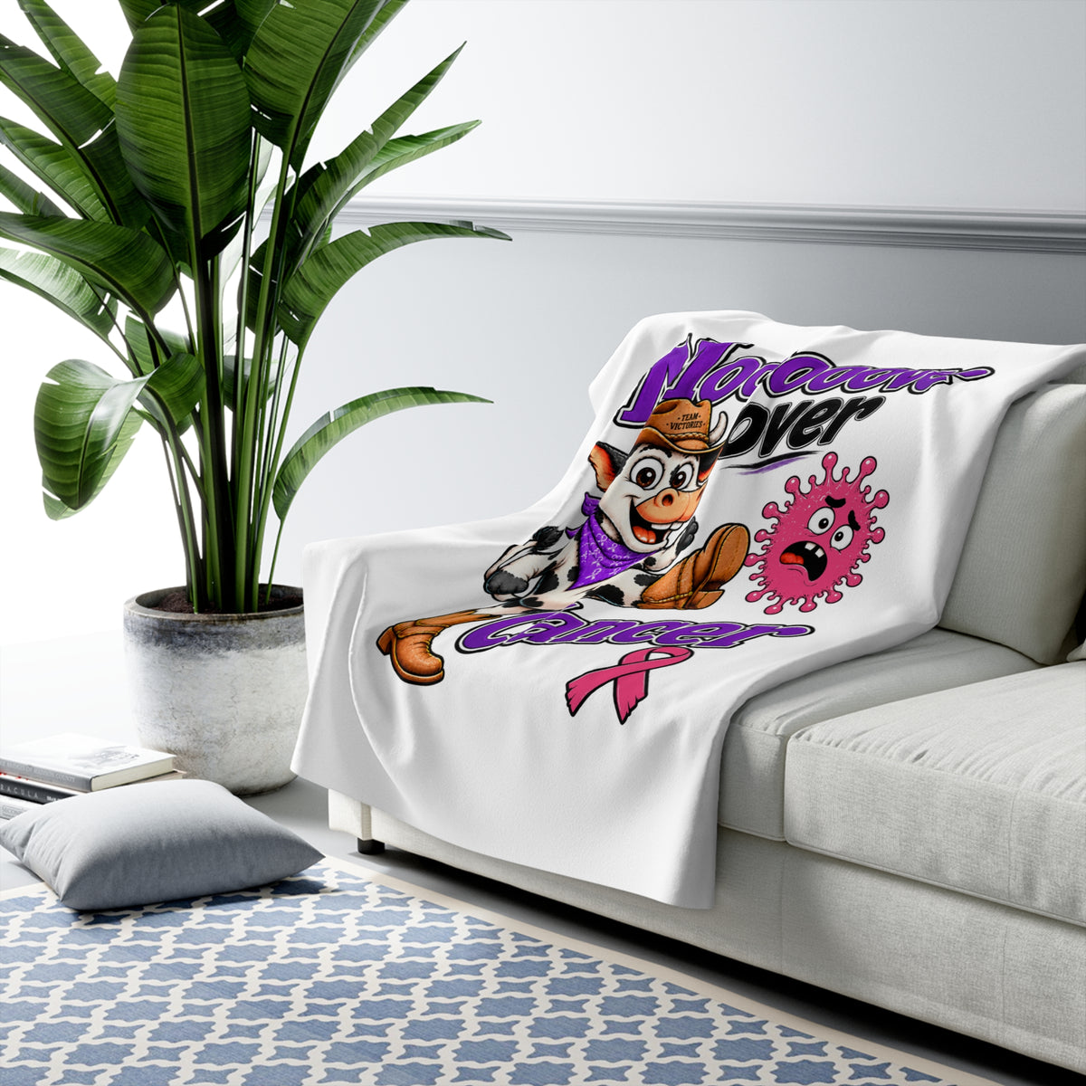 Moooove Over Cancer Breast Cancer awareness blanket draped over a living room sofa