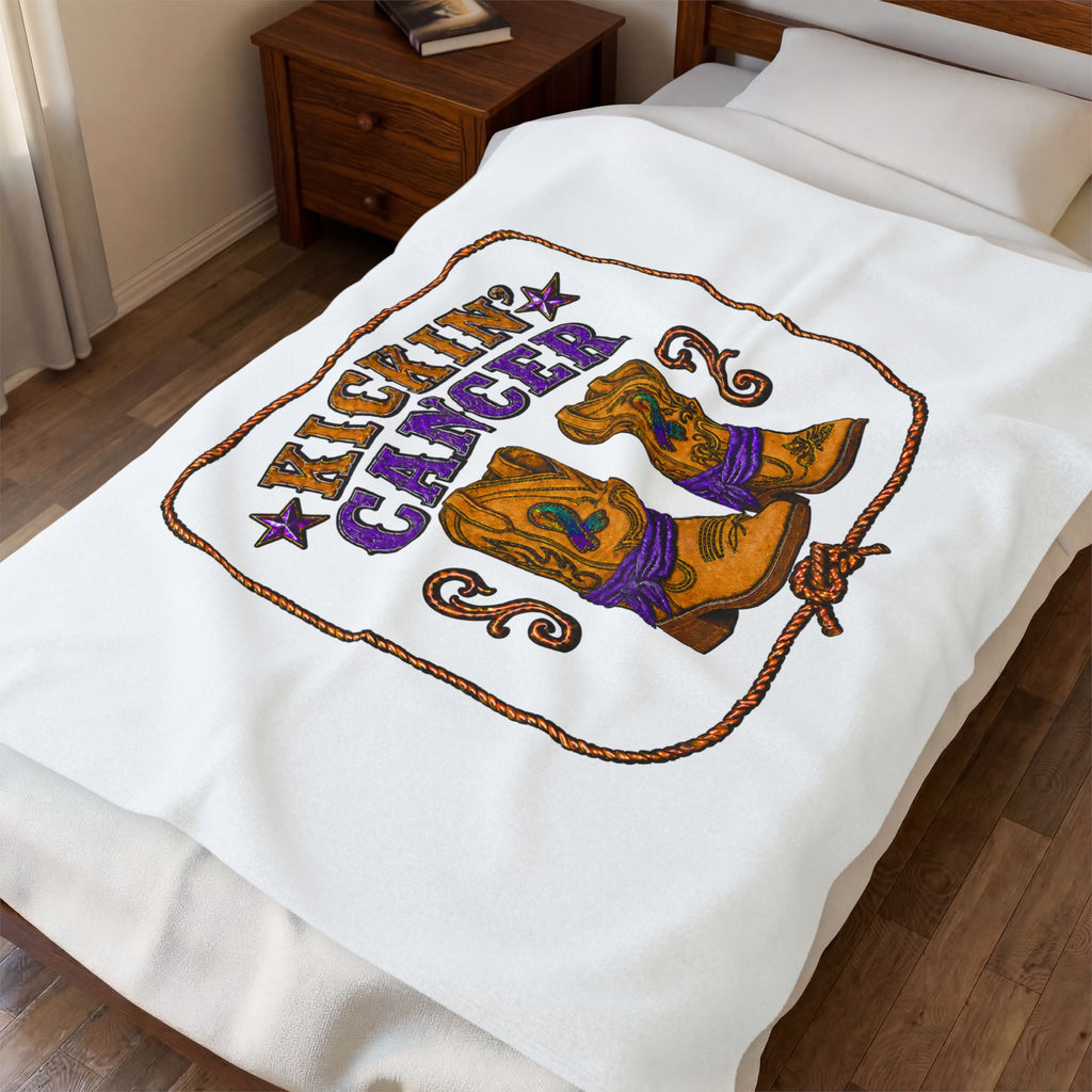 White Kickin' Cancer blanket spread across a bed with cowboy boot and purple awareness artwork